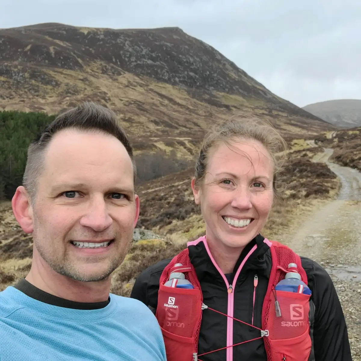 Andrew and Ashley running through the highland landscape of Newtonmore, Scotland