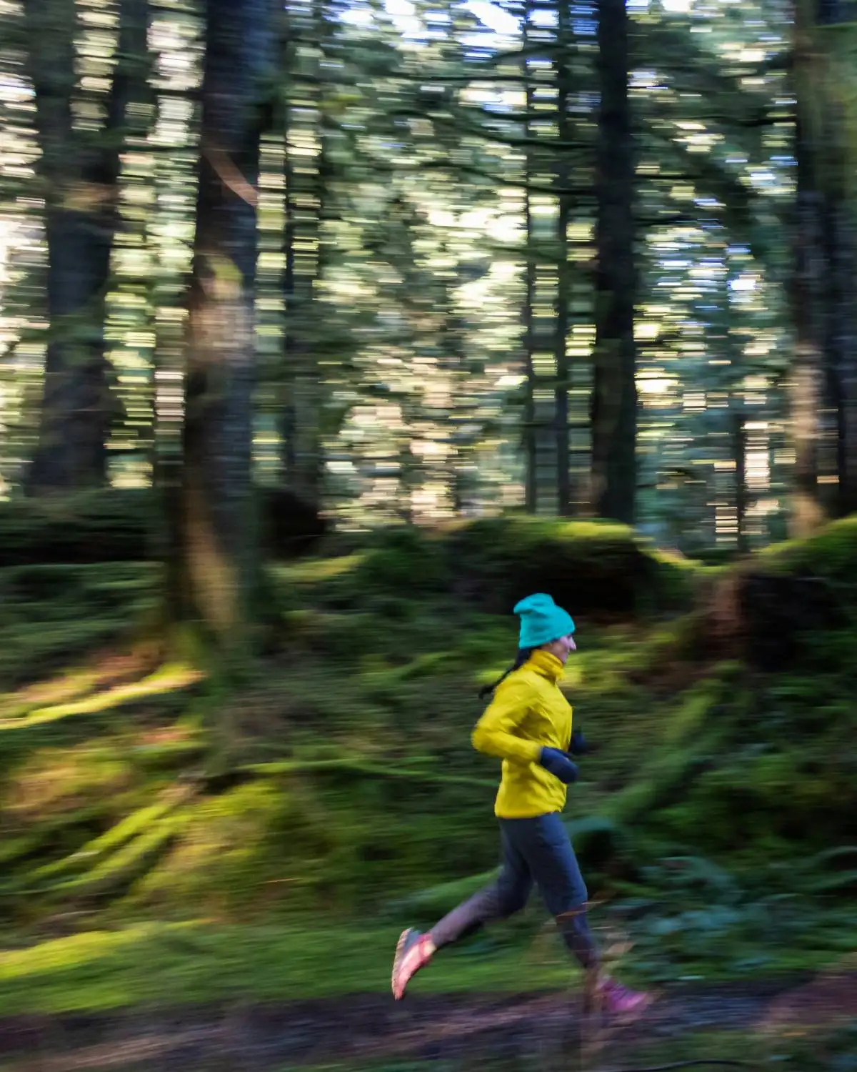 A woman trail running through a wooded path, relaxed and in her element